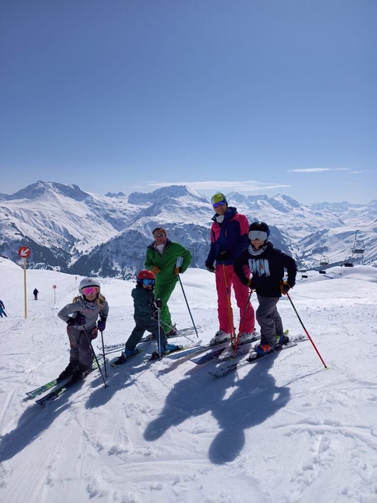 Eine Familie bei Skifahren am Arlberg und wunderschönem blauen Himmel